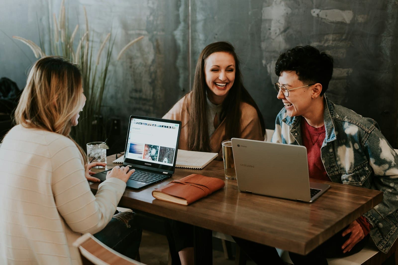 Three people working together on laptops at a shared table