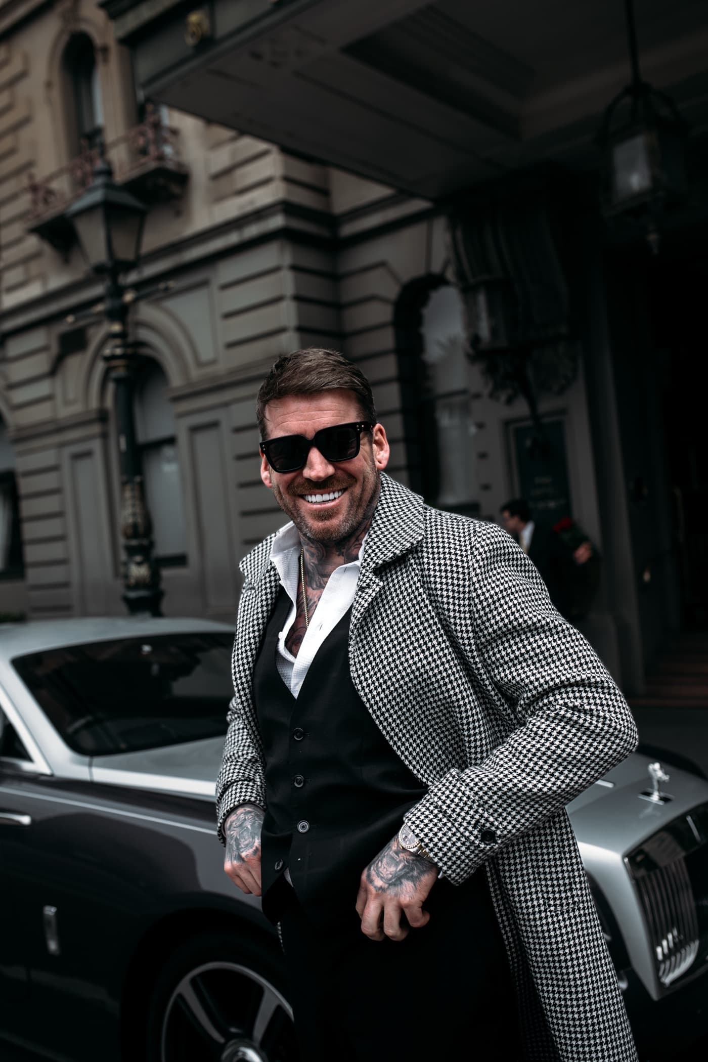 Kevin Mack in London, in a houndstooth coat beside a Rolls-Royce